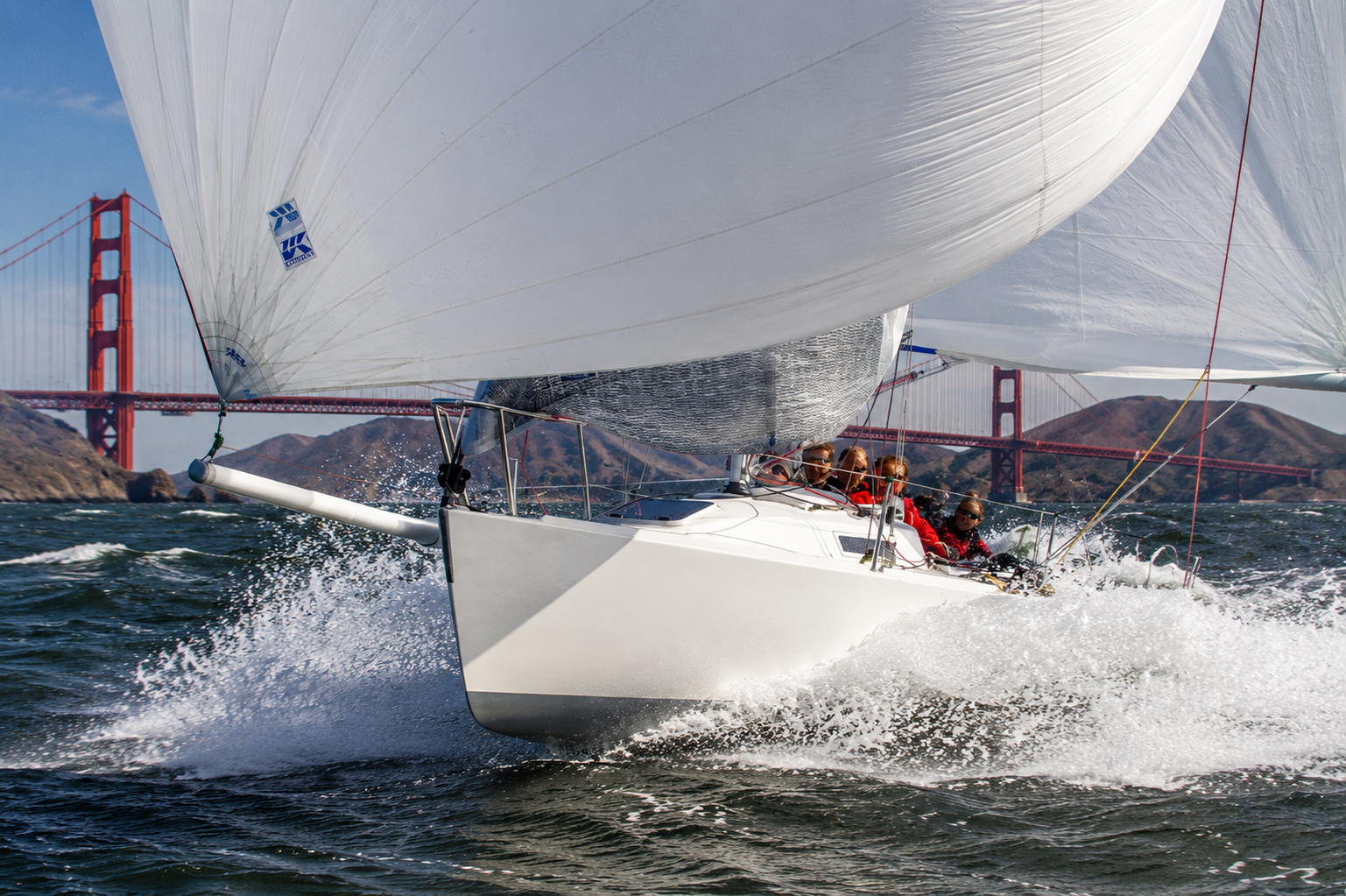J/80 sailing under spinnaker in strong San Francisco Bay conditions near the Golden Gate Bridge